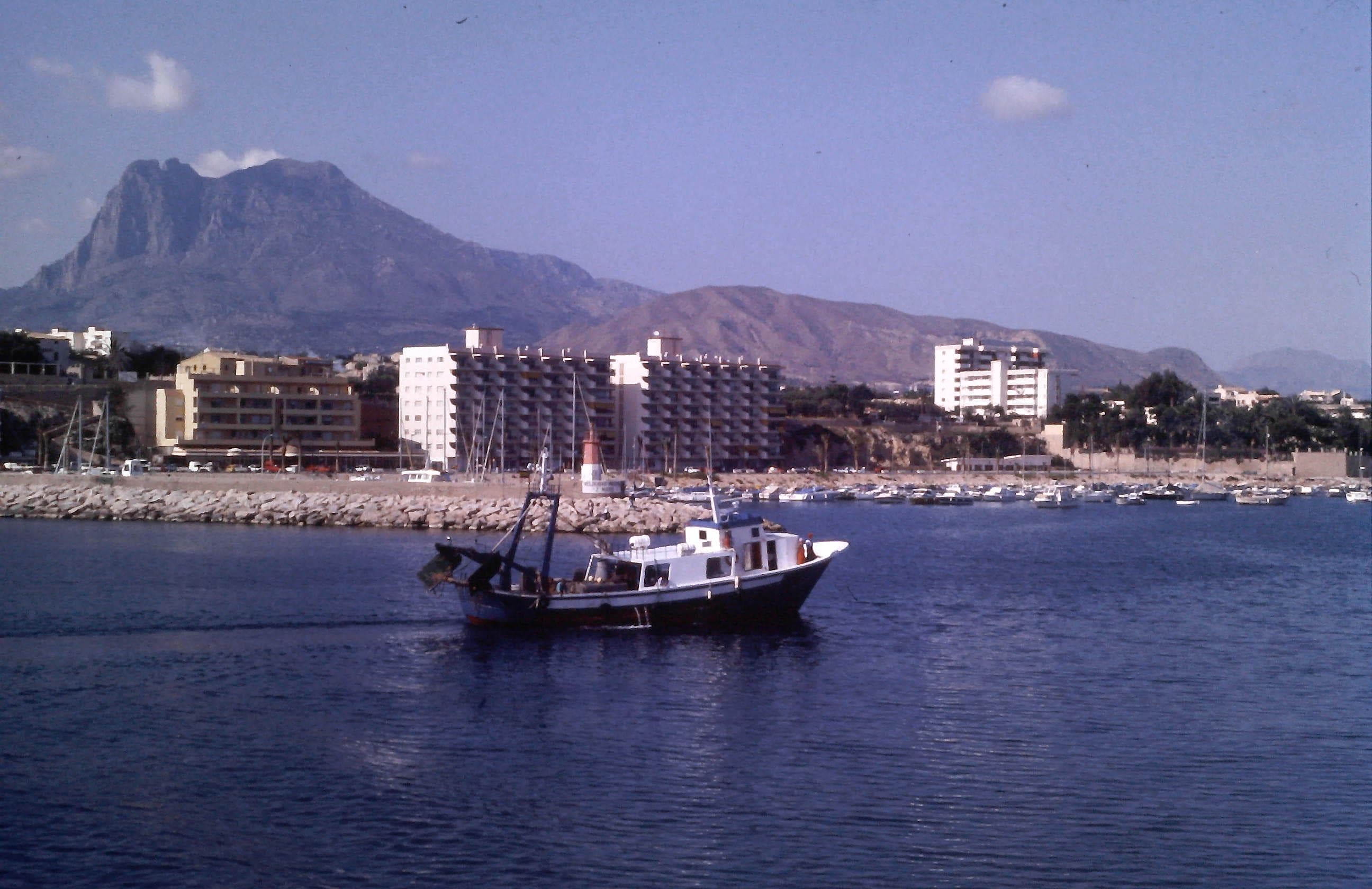 Embarcación pesquera navegando frente al puerto, con la Vila Joiosa en segundo plano y, al fondo, el Puig Campana