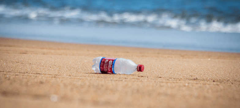 Fotografía de una botella de plástico en la playa. Para Sostenibilidad